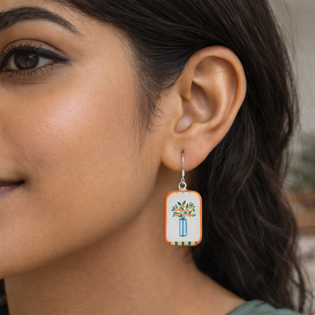 Close-up of a woman wearing a decorative earring with a floral design.