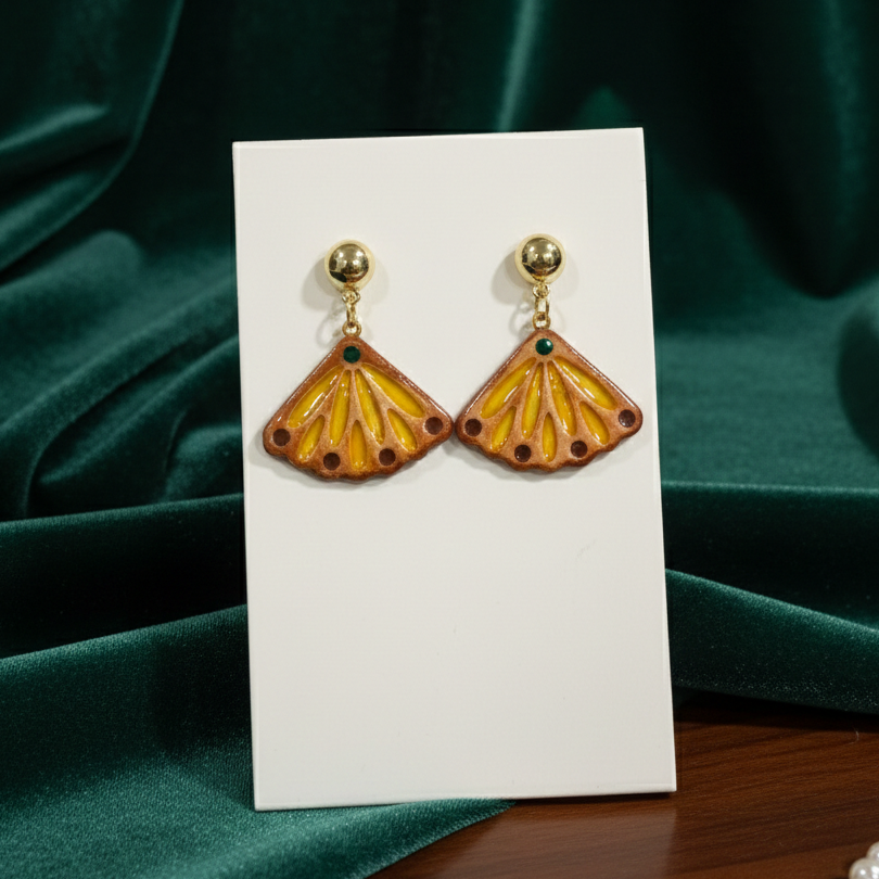Pair of shell-shaped earrings on a white card with a green fabric background