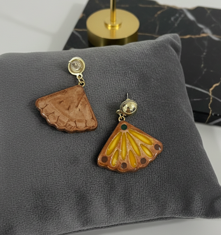 Pair of earrings on a gray cushion with a marble background